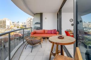 einen Balkon mit einem Sofa und einem Tisch in der Unterkunft Spacious 3 BDR in Florentine in Tel Aviv
