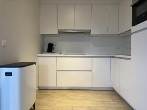 a white kitchen with white cabinets and a wooden floor at Sea Breeze 303 in Nieuwpoort