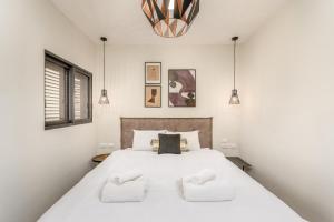 um quarto com uma grande cama branca e 2 almofadas em Unique apartment in Neve Tsedek em Tel Aviv