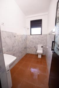 uma casa de banho com um WC, um lavatório e uma janela em Chef Naturelle's Guest House em Kandy