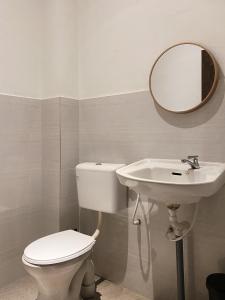 La salle de bains est pourvue de toilettes, d'un lavabo et d'un miroir. dans l'établissement Hinggap Cendana, à Masai