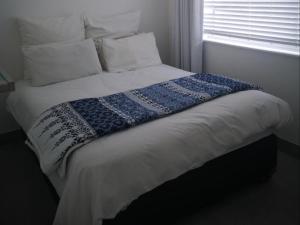 a bed with a blue and white blanket on it at Barefoot Bungalow in Yzerfontein