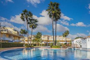 a swimming pool with palm trees and buildings at Jardines de Denia in Denia