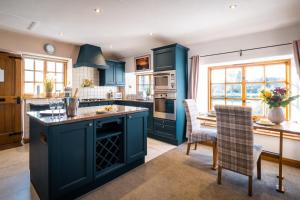 cocina con armarios azules, mesa y sillas en Stunning cottage Grade 2 listed with parking and Hot Tub, en Bowness-on-Windermere