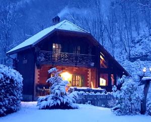 a log cabin in the snow with a light at Vintage riverside house Slapnica, in the Žumberak Nature Park, finnish sauna and jacuzzi in Krašić