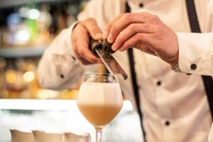 Um chef está a preparar um copo de vinho branco. em Manoir des Indes, The Originals Relais (Relais du Silence) em Quimper