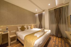 a hotel room with a large bed and a window at Hotel Samudra in Belgaum
