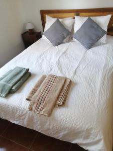 Una cama blanca con toallas y almohadas. en La Pequeña Cercona, en La Granja de San Ildefonso