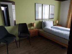 a bedroom with a bed with two chairs and a mirror at Gasthaus Friedegg in Wildhaus