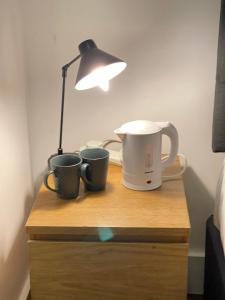 una mesa con dos tazas de café y una lámpara. en ND Hotel - Hyde Park, en Londres