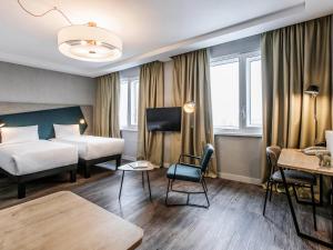 um quarto de hotel com duas camas e uma mesa em Adagio Kyiv Beresteiska em Kiev