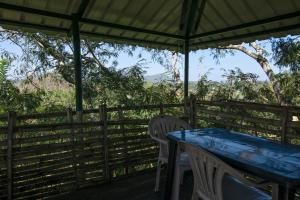 a table and chairs on a porch with a fence at Bamboo Banks Farm & Guest House in Masinagudi