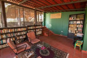 a library with two chairs and a table and books at Bamboo Banks Farm & Guest House in Masinagudi