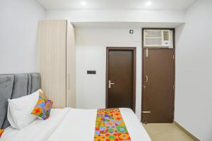 een slaapkamer met een wit bed en een kleurrijke deken bij FabHotel Rasa Arcade in Ghaziabad