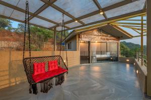 a porch swing with red pillows on a patio at SaffronStays HeavOne Trio, Lonavala in Lonavala +11 photos