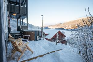 a snow covered patio with a bench and a hot tub at Stamp and sauna! Small farm with fantastic view! in Favang