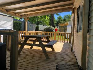 a wooden deck with a picnic table and a bench at Mobilhome 4/6 personnes proche La Palmyre, Royan in Saint-Augustin