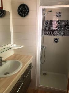 a bathroom with a sink and a shower with a clock at Mobilhome 4/6 personnes proche La Palmyre, Royan in Saint-Augustin