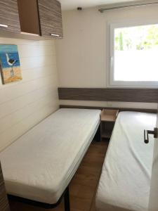 a small room with two beds and a window at Mobilhome 4/6 personnes proche La Palmyre, Royan in Saint-Augustin