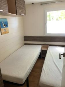 a small room with two beds and a window at Mobilhome 4/6 personnes proche La Palmyre, Royan in Saint-Augustin +4 photos