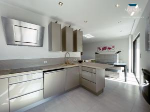 kuchnia z białymi szafkami i zlewem w obiekcie Appartement New Green w mieście Grimaud