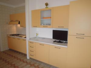 una cocina con armarios amarillos y un monitor en un mostrador en Flat with terrace near the beach - Beahost, en Bibione
