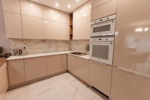 een witte keuken met witte kasten en apparaten bij Beverly Hills House pri potoku by Pinkreal in Solčany