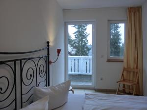 a bedroom with a bed and a view of a balcony at Ferienwohnung NH10 in Hirschburg