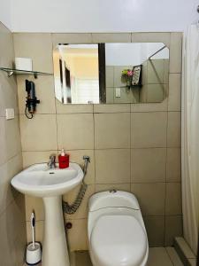 a bathroom with a sink and a toilet and a mirror at Minimalist cozy 1BR unit near BGC and McKinley Hill in Manila