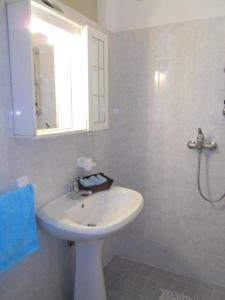 La salle de bains blanche est pourvue d'un lavabo et d'un miroir. dans l'établissement Bright flat with a wide terrace - Beahost Rentals, à Bibione