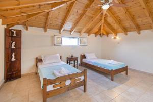 une chambre avec deux lits et un ventilateur de plafond dans l'établissement Pearl Villas Gennadi, à Gennadi