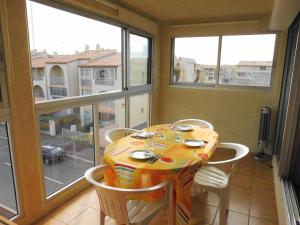 uma sala de jantar com mesa, cadeiras e janelas em NAUTICAP Joli T2 alcôve piscine tennis NAUTICAP Plage Richelieu cap d'Agde em Cap d'Agde