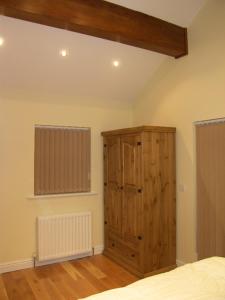 Laxey的住宿－Pinfold Holiday Cottage，一间卧室配有木制橱柜和一张床