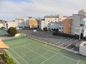 um campo de ténis num parque de estacionamento com edifícios em NAUTICAP Joli T2 alcôve piscine tennis NAUTICAP Plage Richelieu cap d'Agde em Cap d'Agde