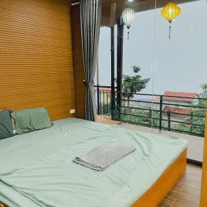 Cama en habitación con ventana grande en Nắng Homestay, en Tam Ðảo
