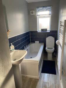 a bathroom with a tub and a toilet and a sink at Lychgate view cottage in Aldbrough