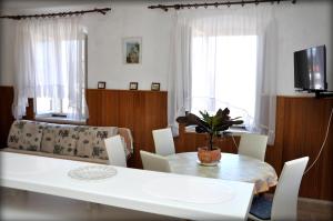 uma sala de jantar com uma mesa branca e cadeiras em Apartments Sunny House em Lumbarda