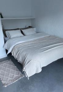 uma cama com lençóis brancos e almofadas num quarto em Casa Olivo em Iznájar