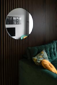 a mirror on a wall with a green couch and a mirrorneau at Apartament ZajkoSki in Duszniki Zdrój
