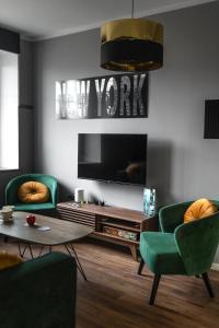 a living room with two green chairs and a tv at Apartament ZajkoSki in Duszniki Zdrój