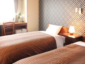 a bedroom with two beds and a table with a lamp at HOTEL LiVEMAX BUDGET Tokyo Hamura Ekimae in Hamura