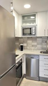 a kitchen with white cabinets and a stainless steel refrigerator at Apartamento Turistico Peñalver Playa 316 in Torrox Costa