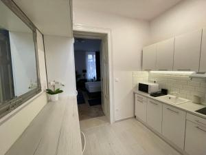 a white kitchen with a sink and a microwave at Fullmoon Luxury Apartment in Szeged