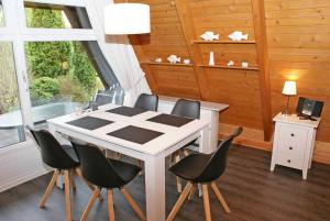 a dining room with a white table and black chairs at wenige Meter bis zum Strand in Damp