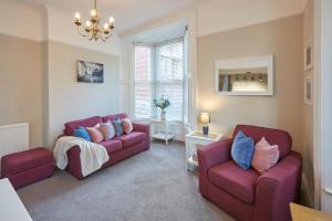 uma sala de estar com dois sofás vermelhos e um lustre em Host & Stay - Sandpiper Apartment em Whitby