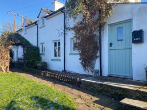 a white house with a green door on a street at Cosy Country Cottage; Brecon Beacons in Crickhowell