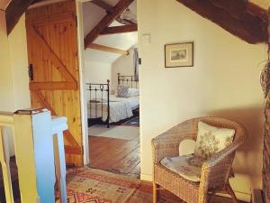 sala de estar con silla de mimbre y dormitorio en Cosy Country Cottage; Brecon Beacons, en Crickhowell