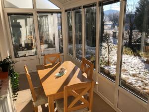 eine Veranda mit einem Holztisch, Stühlen und Fenstern in der Unterkunft Apartman Cypres in Kupres