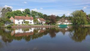 a group of houses next to a lake with a boat at Charming 17th Century 2-Bed Cottage in Medmenham in Medmenham