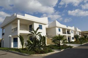 een wit gebouw met palmbomen ervoor bij Baraka Apartments in Scoglitti